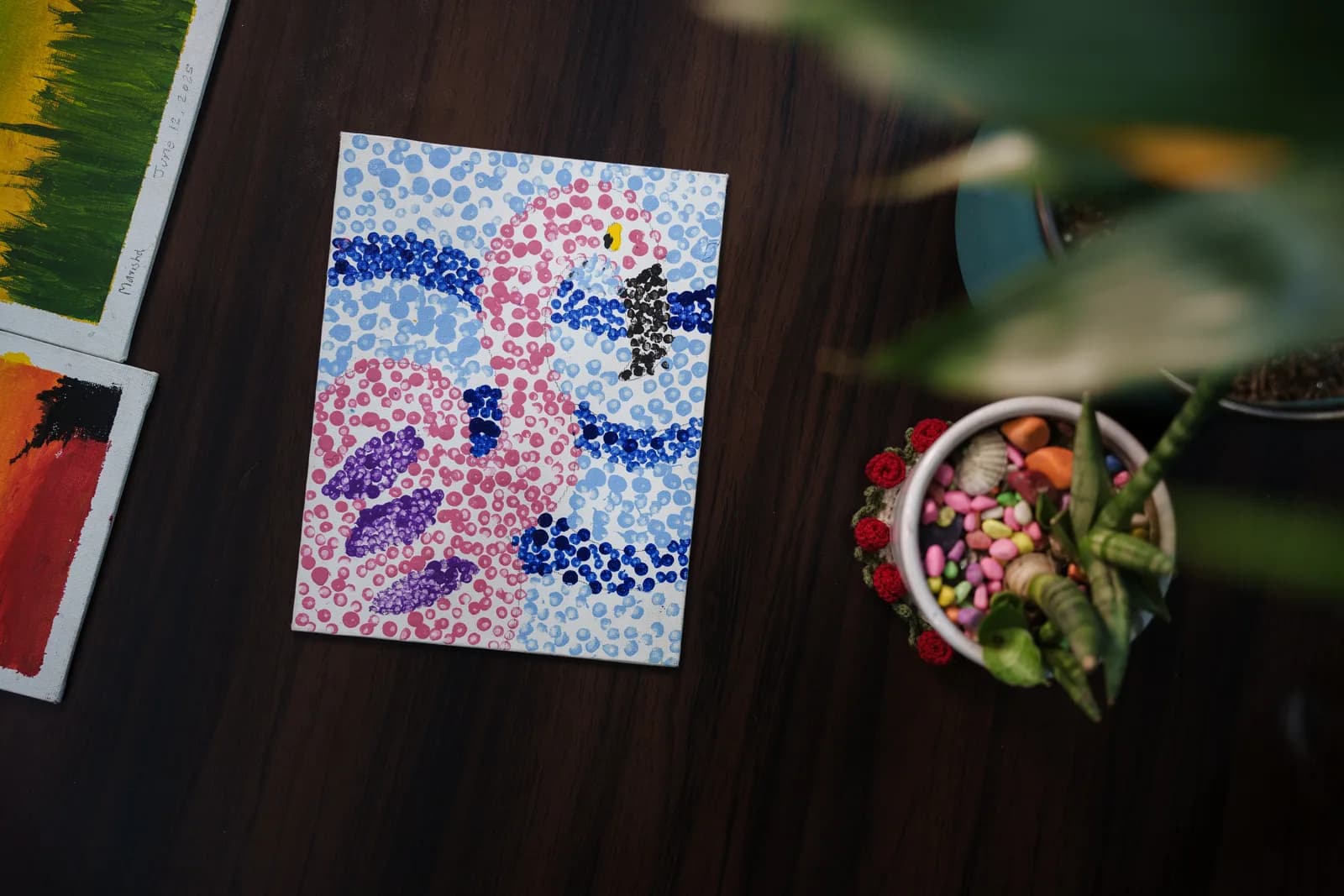 A dotted painting of pink flamingos displayed on a wooden table.