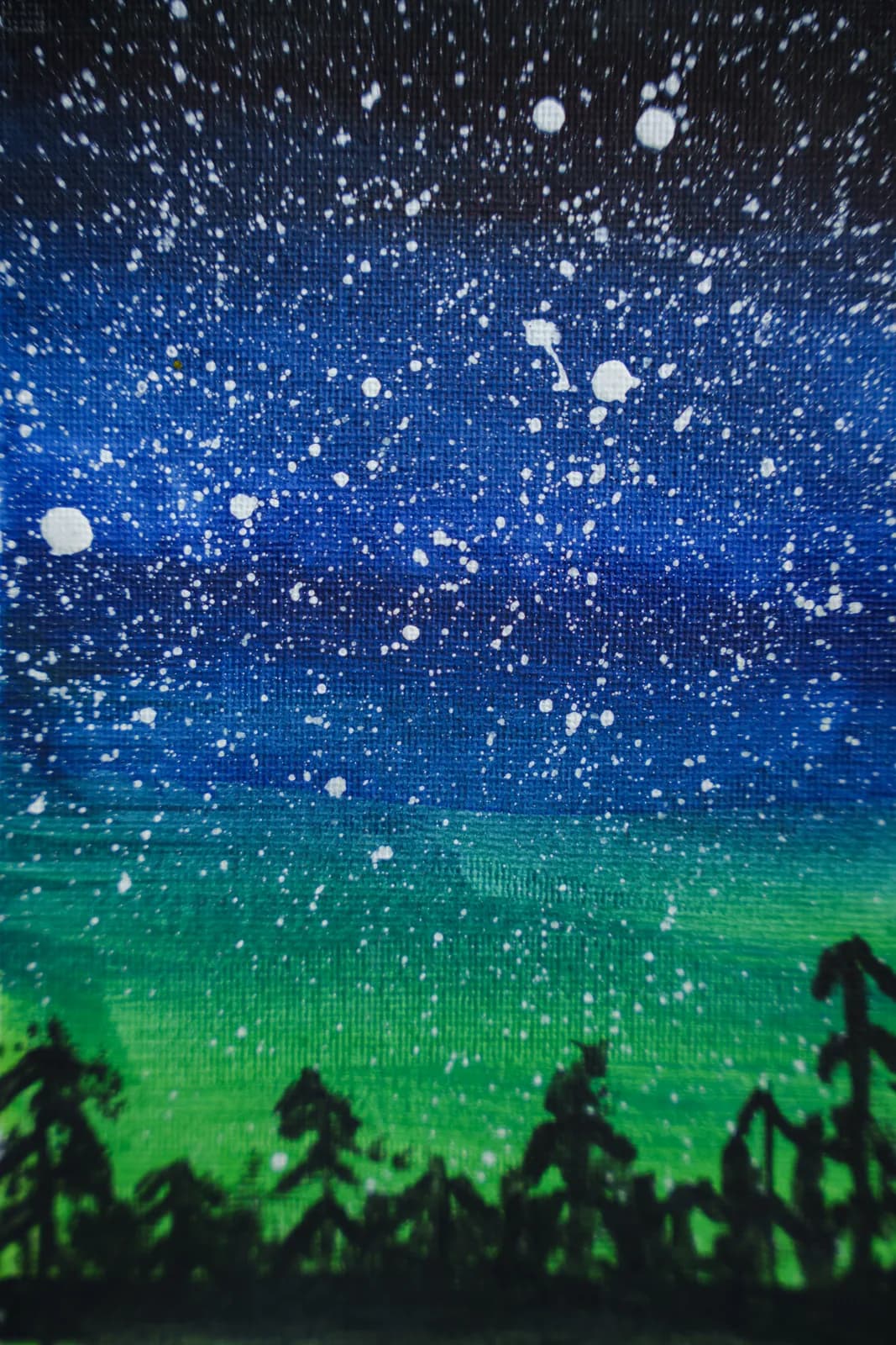 A dense starry sky above green hills and dark tree silhouettes.