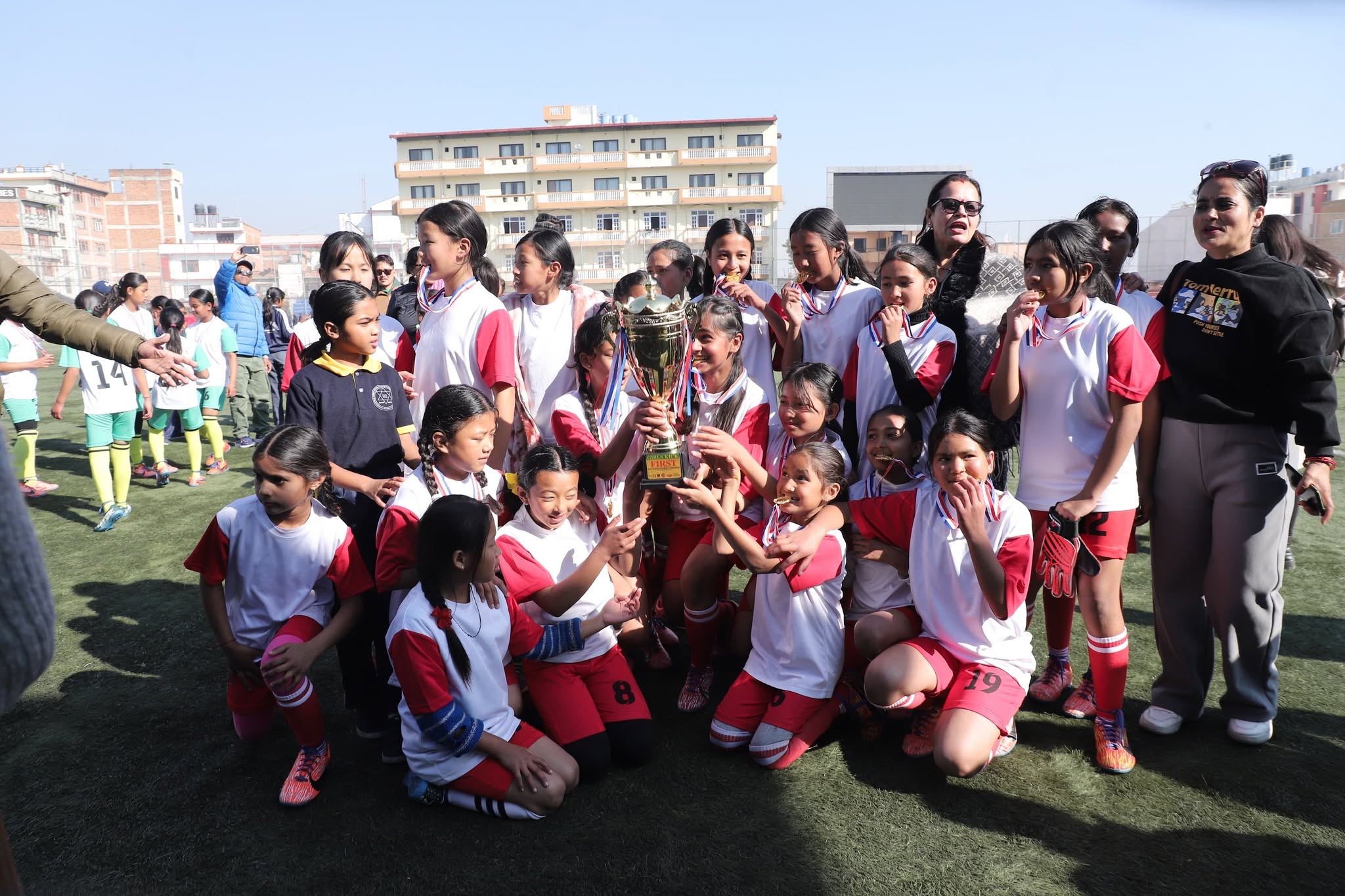 Girls celebrating together with a trophy at an inter-school football tournament